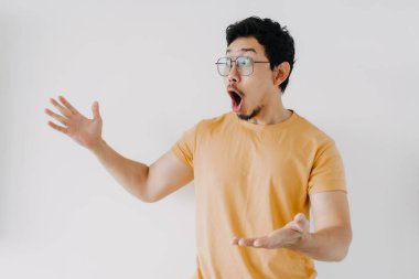 Komik Asyalı adam. Vay ve şok olmuş yüz. Sarı tişört giy..