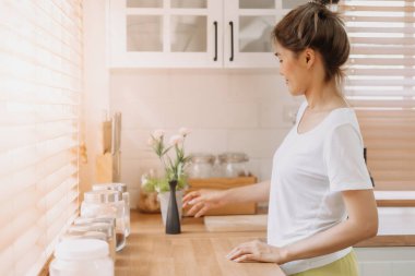 Asyalı kadın ekipman malzemelerini yeniden düzenler ve mutfağı temizler..