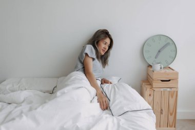 Asyalı bir kadın sabahın 7 'sinde yatağın üzerinde uyanır..