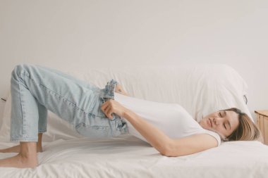 Kotunun fermuarını indiren tatlı Asyalı kadın evinde kanepede uzanıyor..