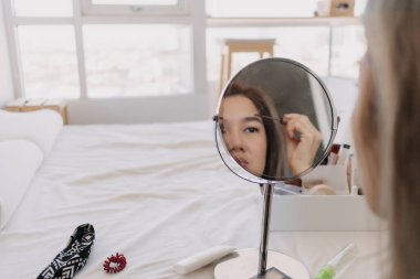 Aynada makyaj yapan Asyalı kadın. Alet edevat ve teçhizatla..