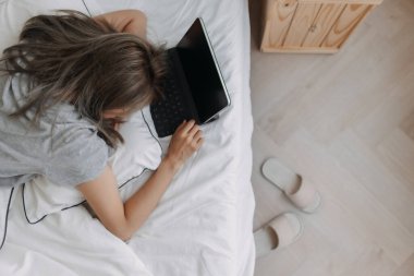 Asyalı kadın sabahları tablet bilgisayarın üzerinde uyur. Erken çevrimiçi çalışma.