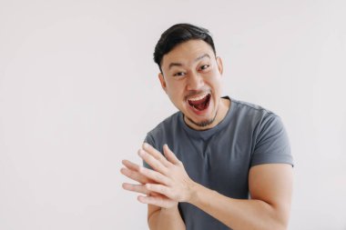 Mavi tişörtlü ve kot pantolonlu mutlu bir Asyalı el çırpıyor.