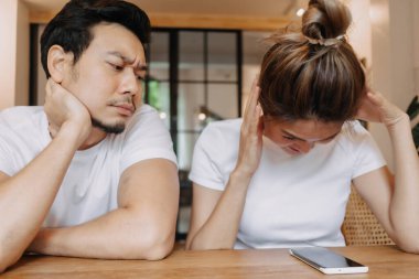 Kadın telefonda uzun süre sohbet edince adam sıkılıyor. Kafedeki Asyalı çift.