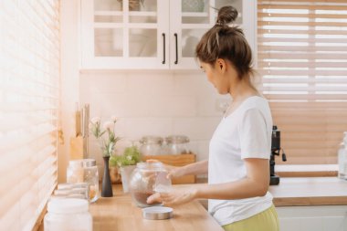 Asyalı kadın ekipman malzemelerini yeniden düzenler ve mutfağı temizler..