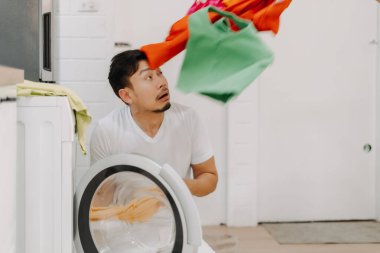 Yüzünde bir yığın kıyafetle yıkanmak için ağlayan komik bir koca..