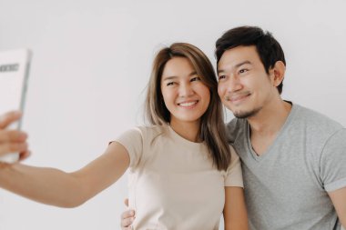 Mutlu komik Asyalı kadın beyaz tenli erkek arkadaşıyla selfie çektirdi..