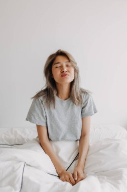 Uykulu ve rüya gören Asyalı kadın sadece yatakta uyanır..