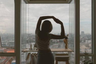 Rahat bir günde evinin camlarının önünde tembelce uzanan Asyalı bir kadın..