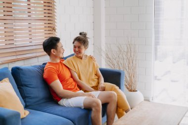 Sevgili Asyalı çift aşığı sıcak evdeki kanepede birlikte oturuyorlar..