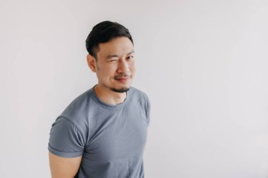 Mutlu Asyalı adam mavi tişört giyer ve kot pantolon giyer kameraya göz kırpar ve gülümser..