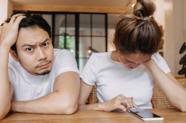 Kadın telefonda uzun süre sohbet edince adam sıkılıyor. Kafedeki Asyalı çift.