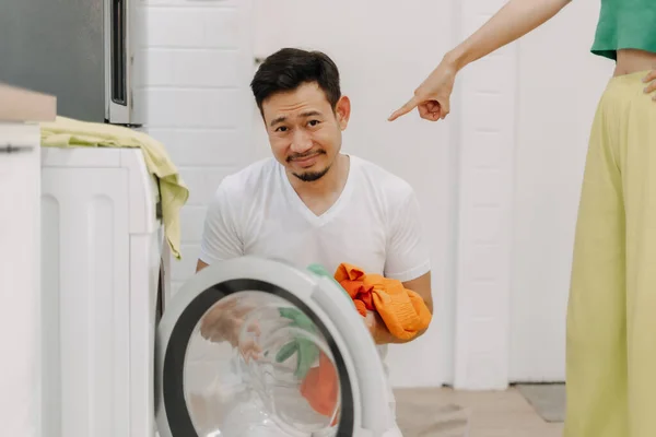 Sad husband being told to wash clothes by his wife. Funny asian couple.