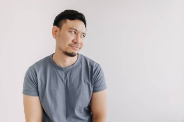 Mavi tişörtlü Asyalı adamın sıkılmış ve yargılanmış yüzü beyazlar içinde izole edilmiş..