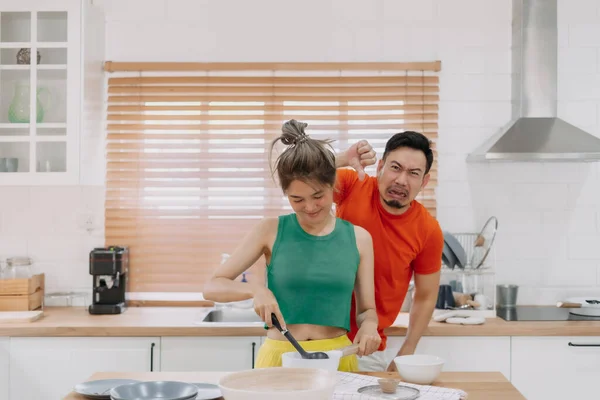 Asian couple, husband feels worry behind his wife while she is cooking for him.