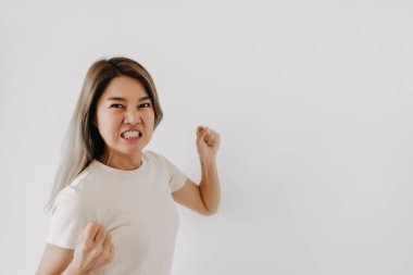 Beyaz tişörtlü Asyalı bir kadının kızgın yüzü beyaza bürünmüş..