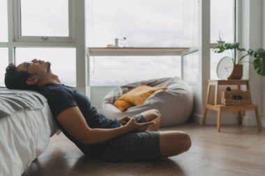 Yalnız Asyalı adam dairesinde tek başına sosyal medya için akıllı telefonu kullanıyor..