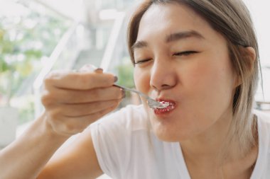Kafede dikkatsizce pasta yiyen mutlu Asyalı kadının komik yüzü..