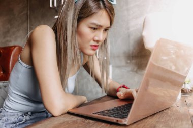 Serbest çalışan Asyalı kadın ciddi ve bilgisayardaki çalışma sorunundan rahatsız..