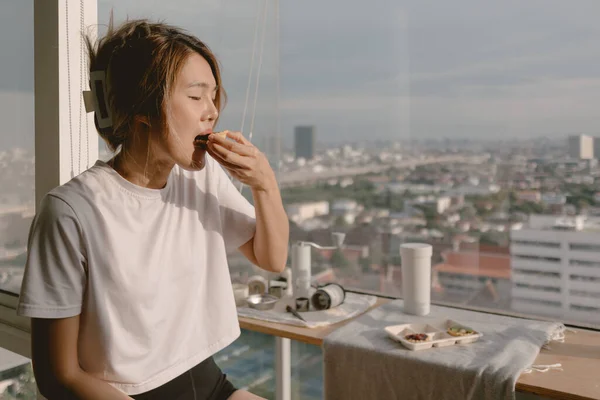 Relax asian woman eating at balcony window good warm vibes weekends lifestyle.