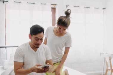 Komik Asyalı çift. Akıllı telefondan konuşan, dikizci bir eş..