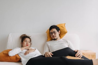 Sıkıcı ve depresif Asyalı sevgili çift boş bir günde kanepede yatıyor..