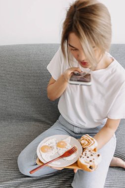 Asyalı kadın basit ve kolay ev yapımı kahvaltısının fotoğrafını çekiyor..