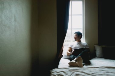 Yalnız bekar bir adam karanlık bir yatak odasında tek başına oturur ve dinlenir..