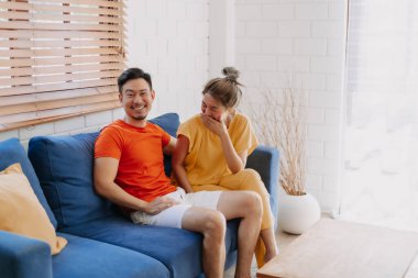 Sevgili Asyalı çift aşığı sıcak evdeki kanepede birlikte oturuyorlar..