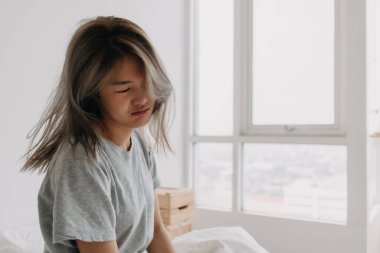 Komik suratlı, uykucu Asyalı kadın sabah uyanıyor, başı dönüyor ve tembel..