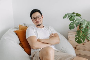 Mutlu Asyalı adam, bir gün oturma odasındaki armut çuvalında rahatla..