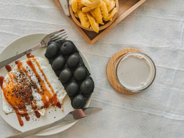 Sabahları kızarmış yumurta ve ananas servis edilen renkli waffle seti..