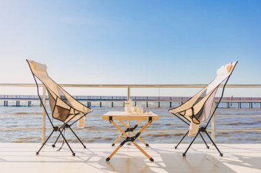 Katlanan sandalyeli ve masalı piknik seti, el değirmeni ve kahve makinesi, güzel parlak gökyüzü ve okyanus tatili..