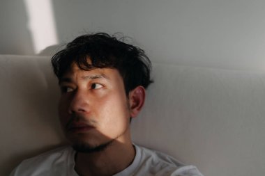 Yalnız Asyalı adamın suratını kapatın. Düşük ışık odasında depresif ve sıkılmış hissedin..