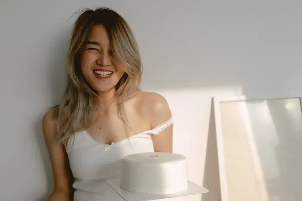 Smile and playful sexy and cute Asian woman feeling happy with her birthday cake in the bedroom.