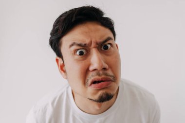 Beyaz tişörtlü Asyalı komik ve hayal kırıklığına uğramış adam beyaz duvarda izole edilmiş..