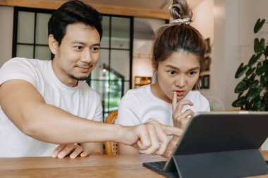 Erkek, kafede bilgisayar tabletli kadını öğretiyor ve gösteriyor, Asyalı çift..