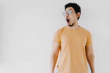 Komik Asyalı adam. Vay ve şok olmuş yüz. Sarı tişört giy..