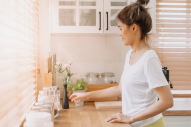 Asyalı kadın ekipman malzemelerini yeniden düzenler ve mutfağı temizler..