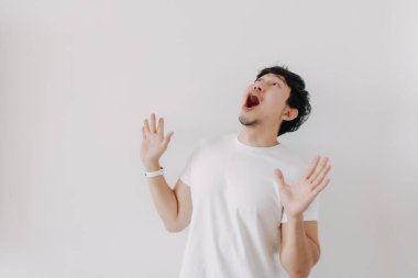 Beyaz tişörtlü sıradan Asyalı adamın beyaz arka planda izole edilmiş yüz ifadesi..