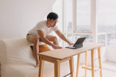 Komik Asyalı adam işinden çok mutlu ve heyecanlı. Bilgisayar tabletindeki başarısı ve zaferi..