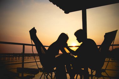 Çift aşığının silueti balayı denizinde romantik günbatımında oturup rahatlar. Yüksek kalite fotoğraf