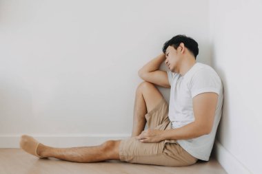 Yalnız Asyalı adam odanın köşesinde oturuyor..