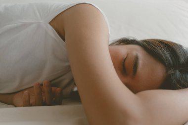 Asyalı kadın yorgun ve hastayken kanepede uyuyakalıyor..