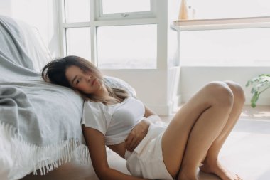 Asyalı üzgün kadın sıkıcı bir günde yerde oturuyor. Sıkıldım ve hayattan yoruldum..