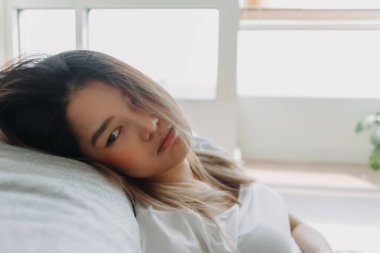 Asyalı üzgün kadın sıkıcı bir günde yerde oturuyor. Sıkıldım ve hayattan yoruldum..