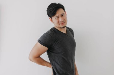 Siyah tişörtlü Asyalı adam beyaz duvarda izole edilmiş sırt ağrısından rahatsız ve acı çekiyor..