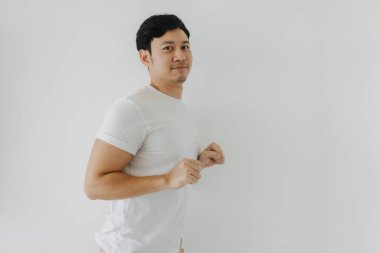 Mutlu Asyalı sakallı adam yumruğunu kaldırıyor, eğlenceli dans pozları veriyor, beyaz arka plan duvarının arkasında tek başına kameraya bakıyor.. 