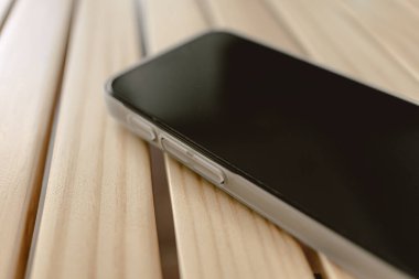 Cep telefonunun kapağı açık. Masanın üzerinde beyaz bir çanta var..