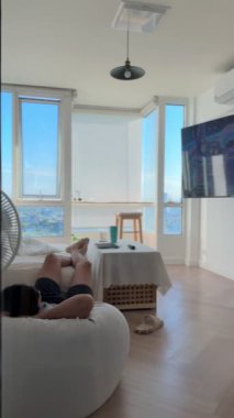 Dikey video, Asyalı bir adam sıcak yaz günü apartmanda kestiriyor..